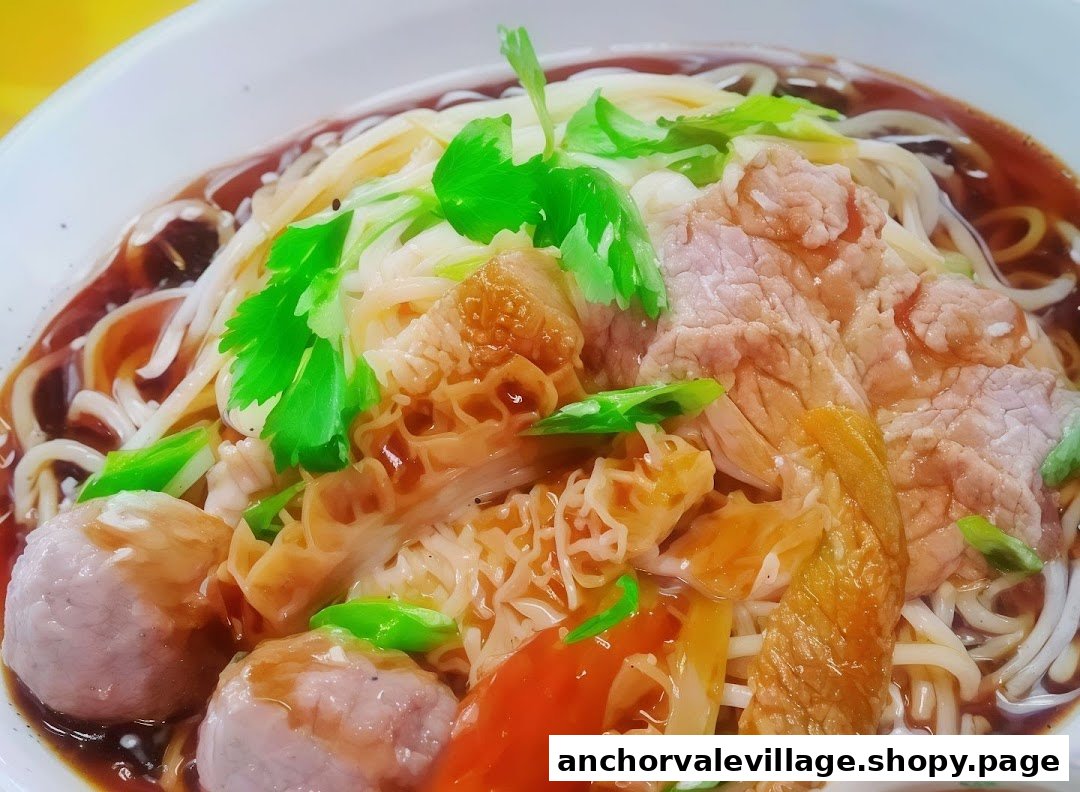 A close-up of a delicious bowl of Hainan beef noodles with various cuts of beef, tripe, and meatballs.
