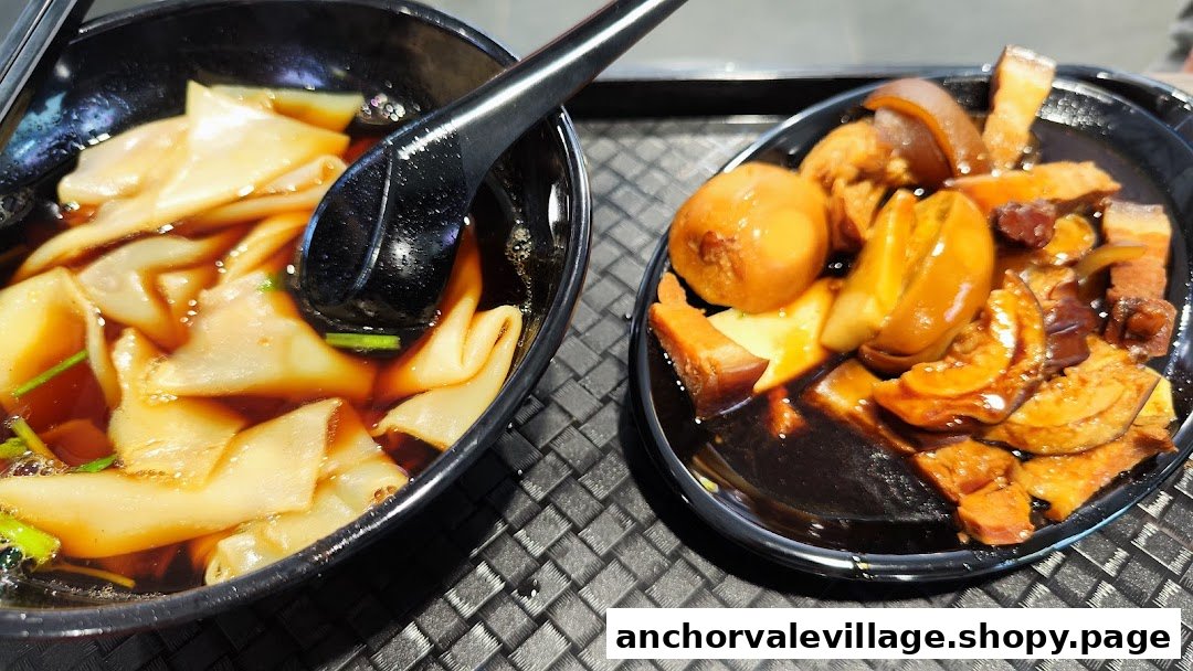 A close-up of Hakka noodles in broth and a side of braised meats and eggs.