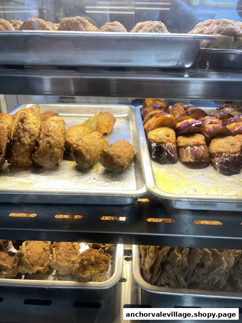 A display case filled with various freshly fried Hakka Yong Tau Foo items, including stuffed eggplant and bitter gourd.