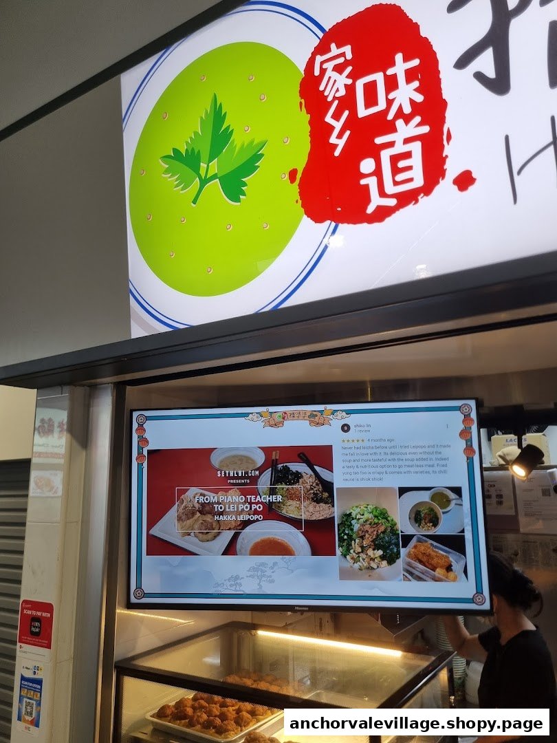 A vibrant food stall featuring a digital display showcasing Hakka cuisine and customer reviews.