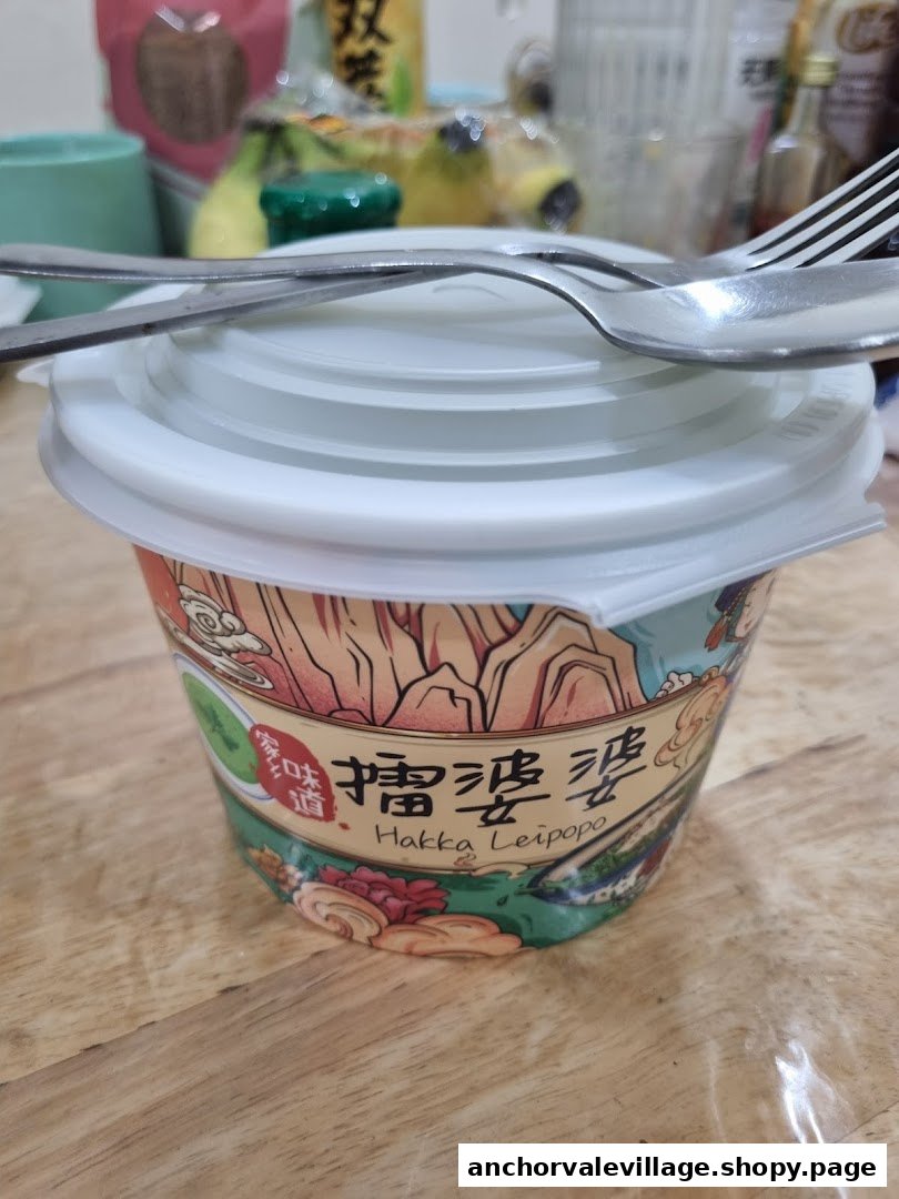 A cup of Hakka Leipopo with a lid and cutlery on a wooden table.