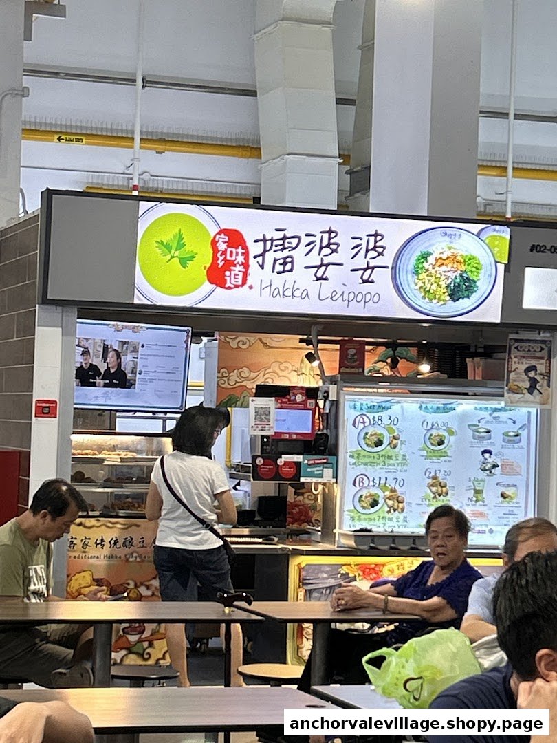A bustling food stall, Hakka Leipopo, showcasing its menu board with set meal options and customers.