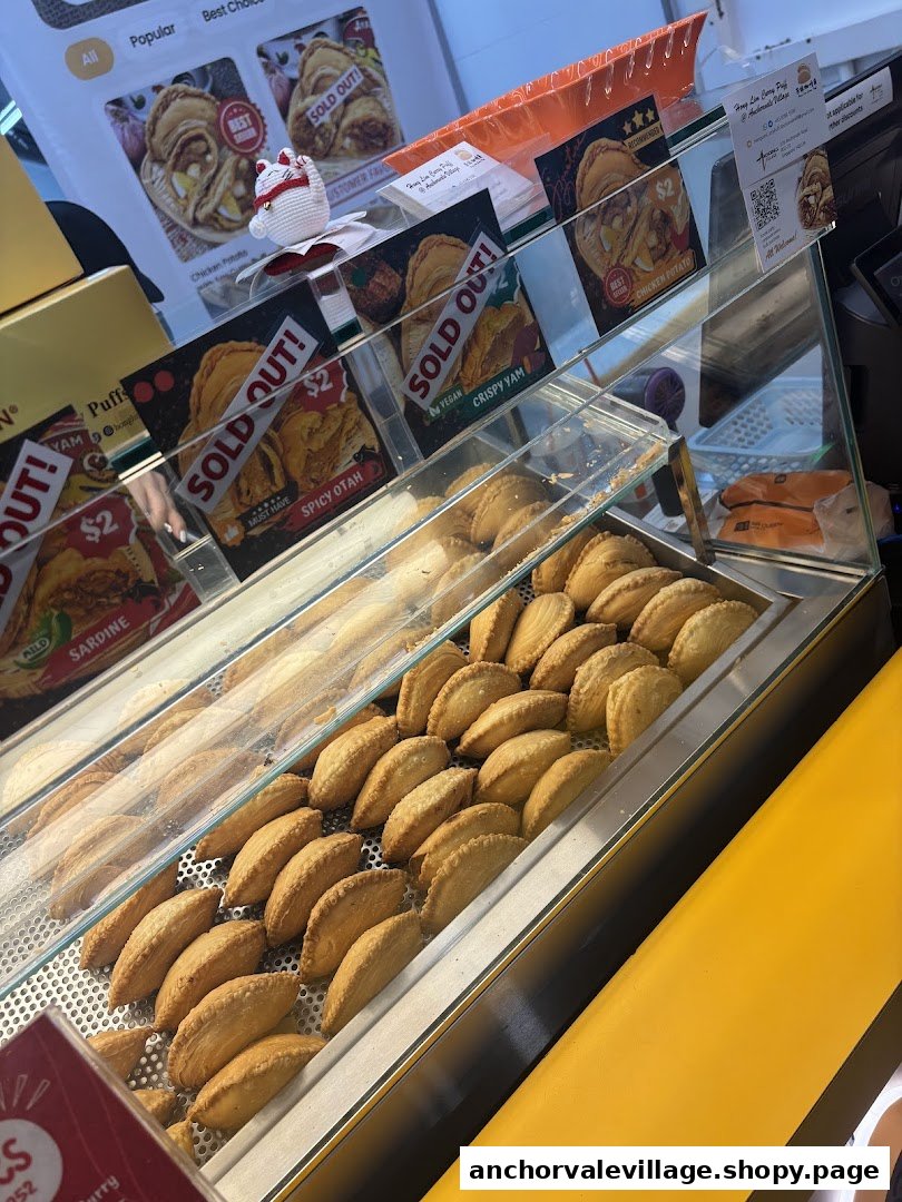 A display case showcasing rows of golden-brown curry puffs with promotional signs.