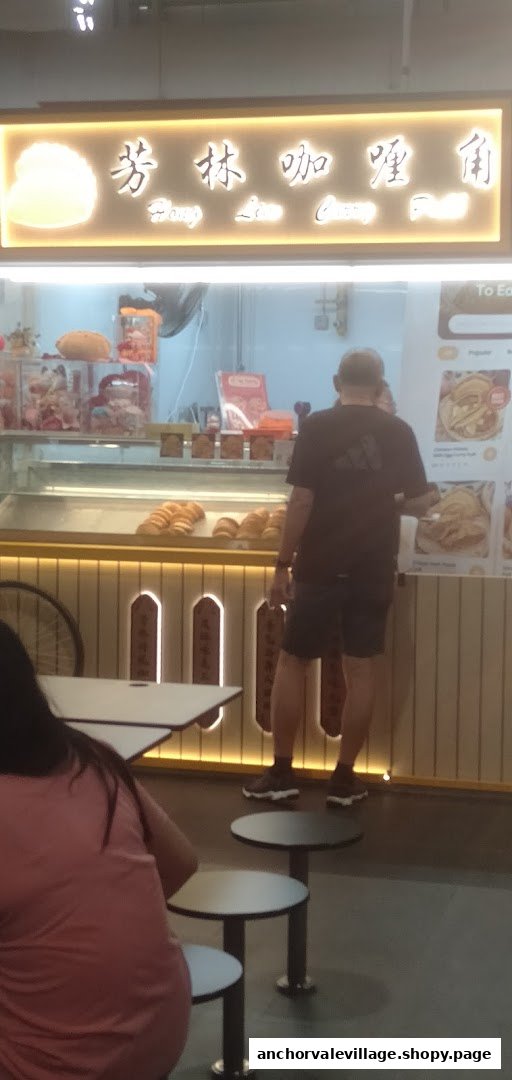 A customer at the counter of Hong Lim Curry Puff, with pastries displayed and menu boards visible.