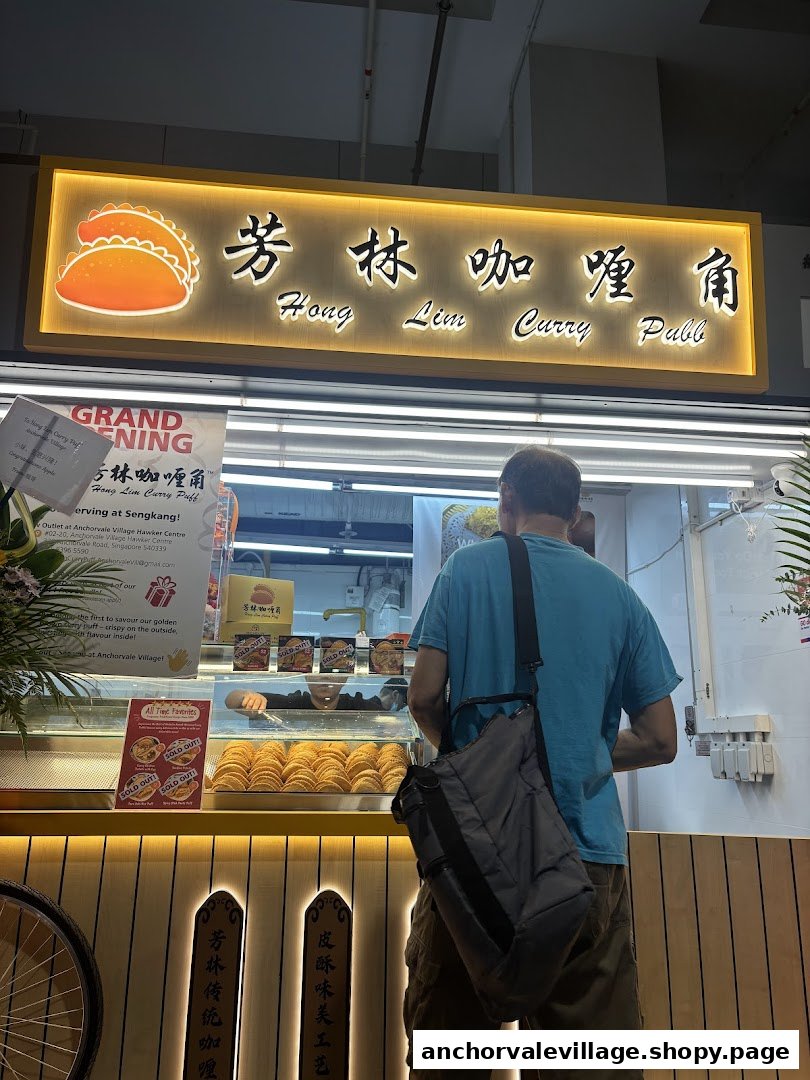A customer stands before the brightly lit Hong Lim Curry Puff shop front, showcasing rows of golden curry puffs.