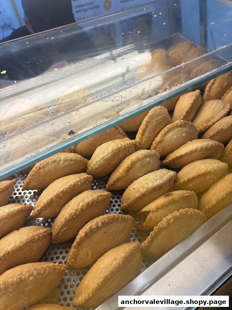 A display case filled with rows of golden-brown, freshly baked curry puffs.