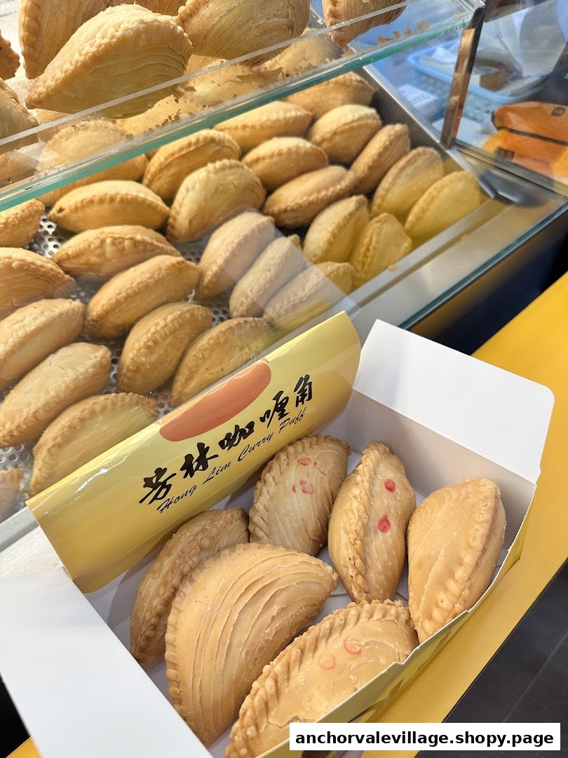 A box of freshly baked curry puffs from Hong Lim Curry Puff, with more in a display case.