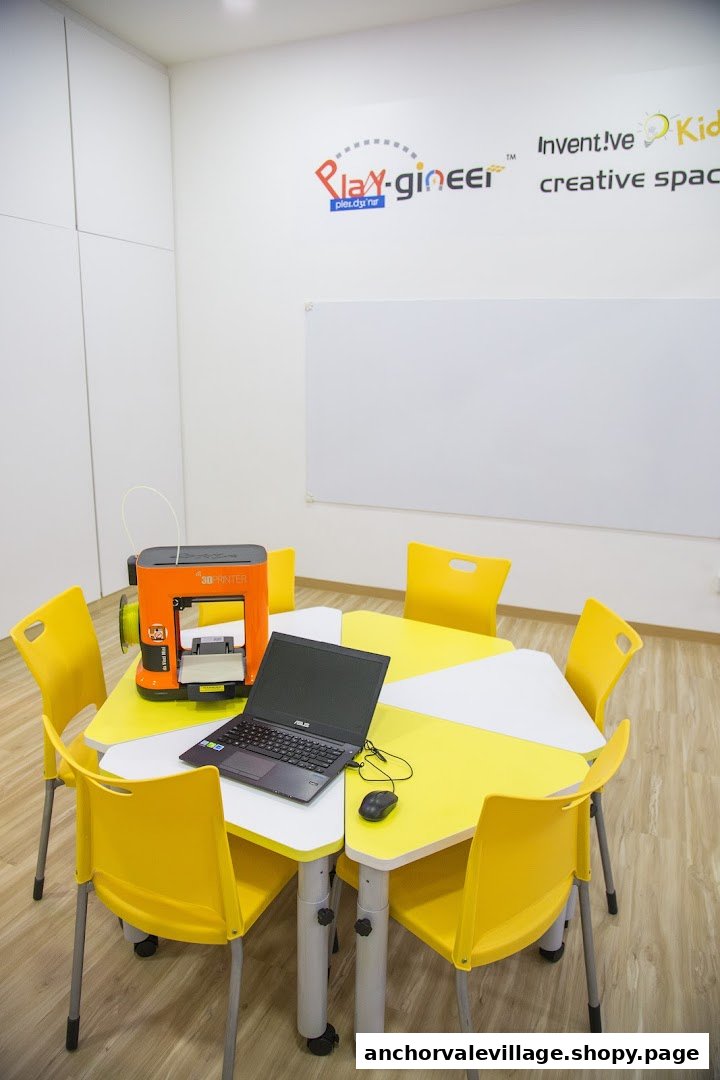 A bright classroom setup with a 3D printer, laptop, and yellow chairs for STEM learning.