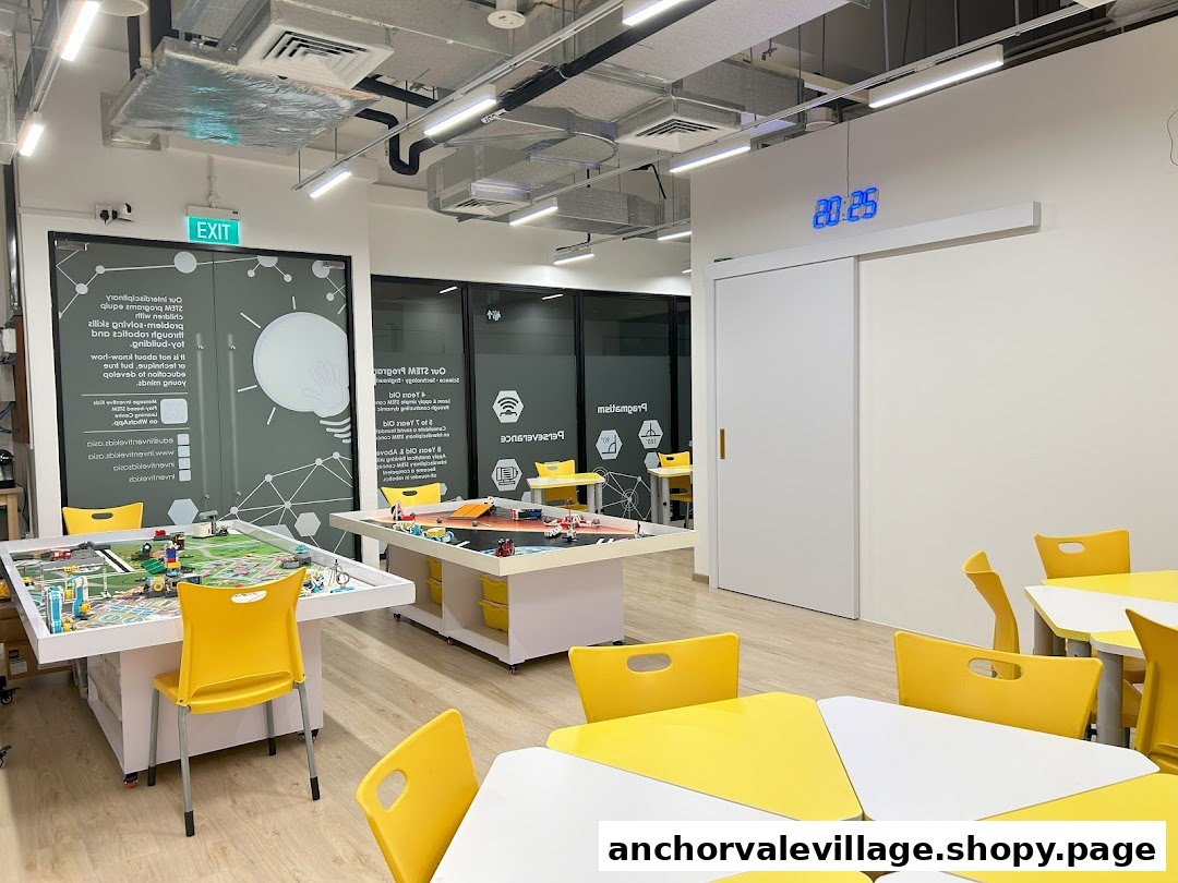 A bright, modern STEM learning center interior with activity tables, yellow chairs, and educational displays.