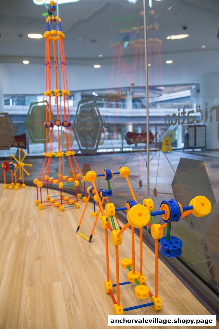 Colorful STEM building toys, including a tall tower and other structures, displayed on a wooden floor inside a learning center.