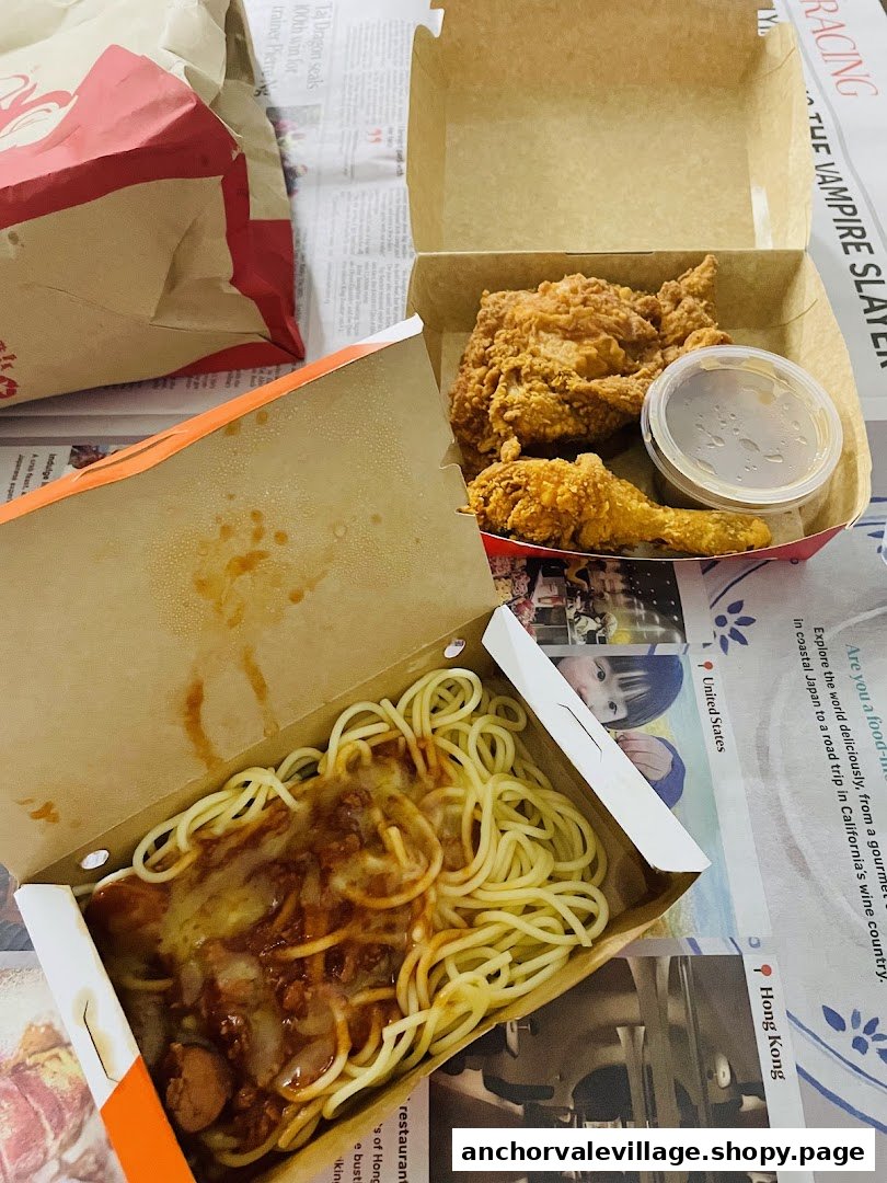 A top-down view of Jollibee's signature fried chicken and sweet spaghetti in takeout boxes.