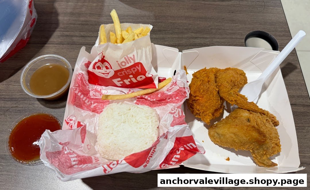 A Jollibee meal featuring fried chicken, Jolly Crispy Fries, rice, gravy, and ketchup on a table.