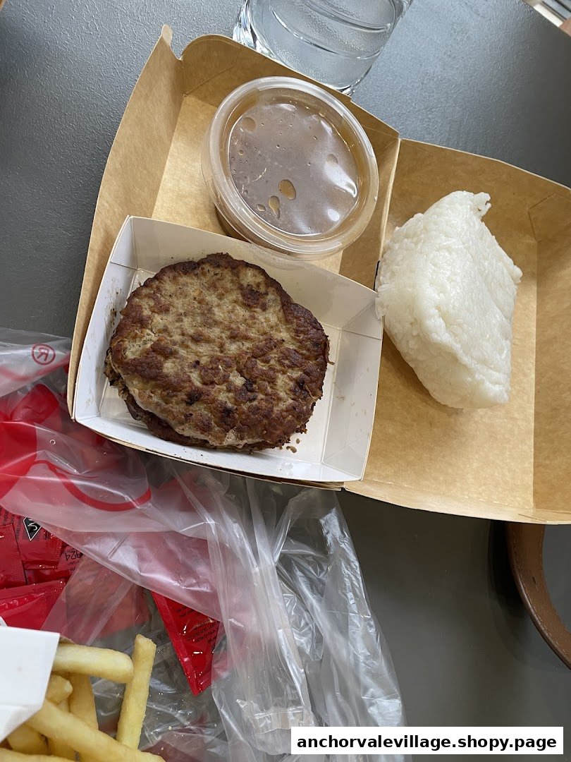 A Jollibee meal featuring a burger steak, rice, gravy, and fries on a table.