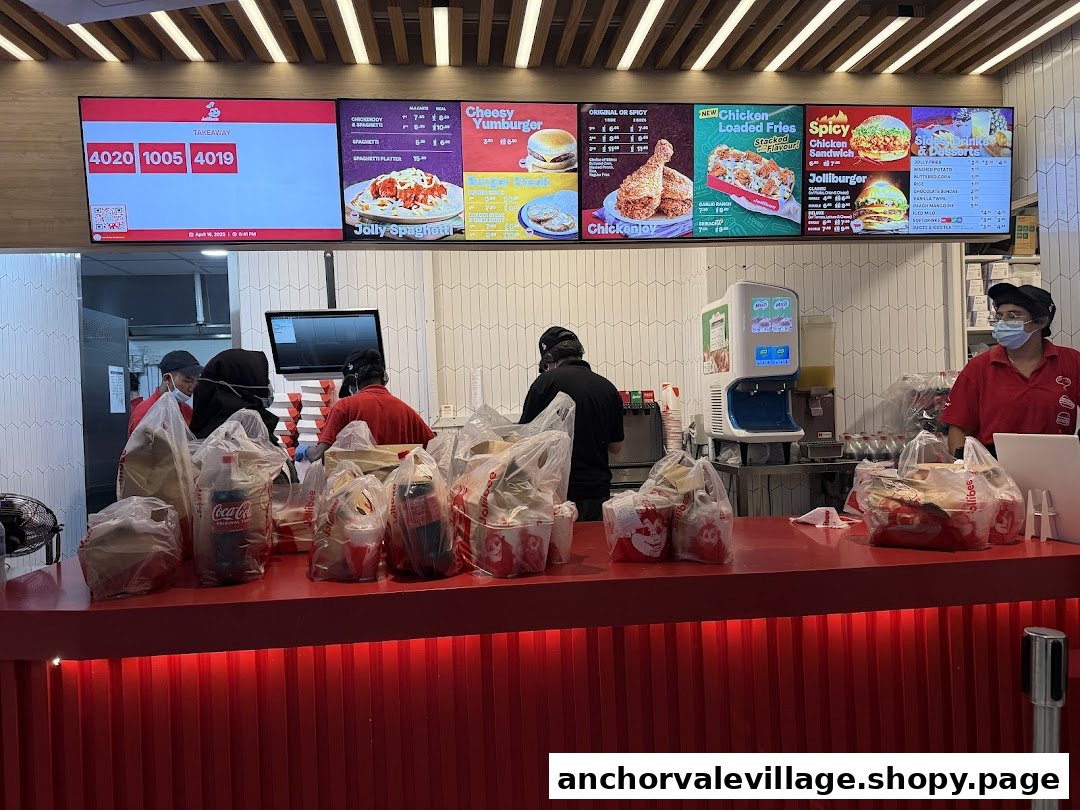 Busy Jollibee counter with staff preparing takeaway orders under digital menu boards.