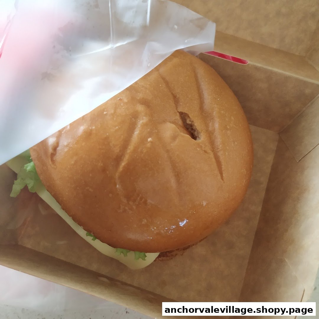 A delicious burger from Jollibee, presented in a brown takeaway box with white wrapping.
