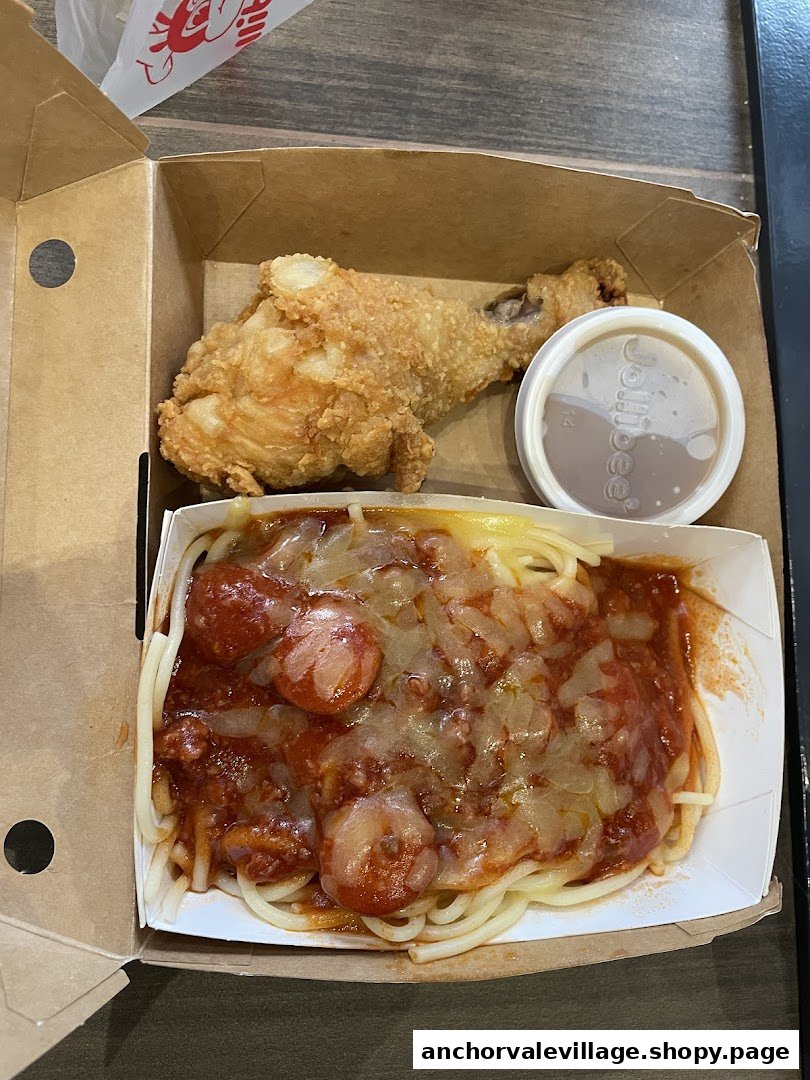 A Jollibee meal featuring crispy fried chicken, Jolly Spaghetti, and gravy in a takeout box.