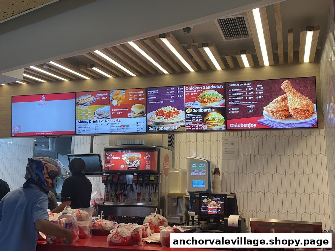 Digital menu boards displaying Jollibee's offerings above a busy service counter.