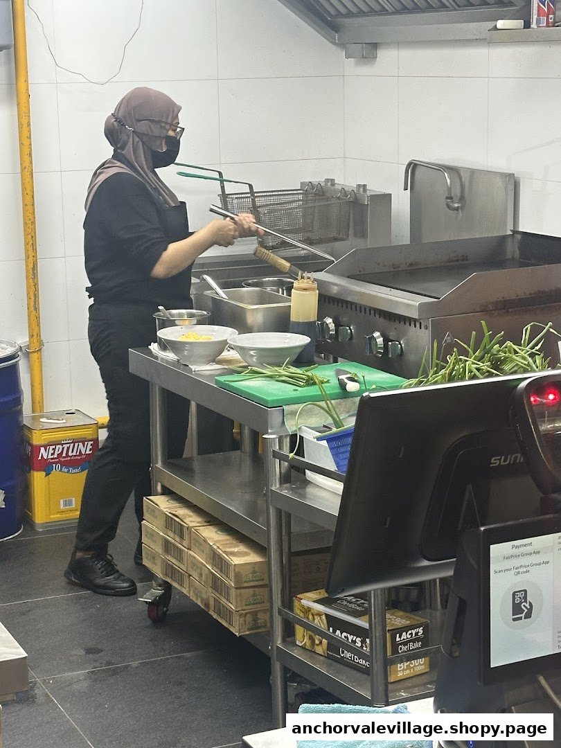 A chef in a professional kitchen preparing food with fresh ingredients and cooking equipment.