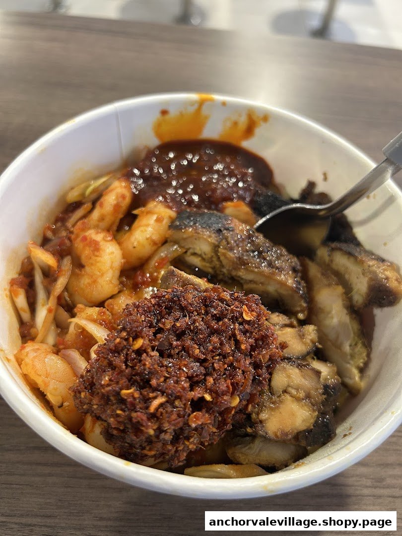 A close-up of a delicious Kawan Bowl featuring grilled chicken, prawns, and spicy chili paste.