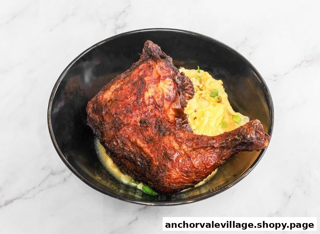 A close-up of a crispy roasted chicken leg served with a creamy side dish in a black bowl.