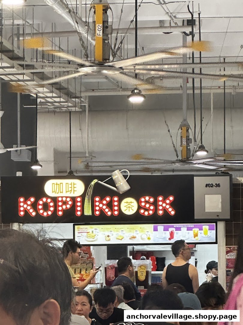 A bustling Kopi Kiosk counter with its illuminated sign, serving customers in a vibrant food court setting.
