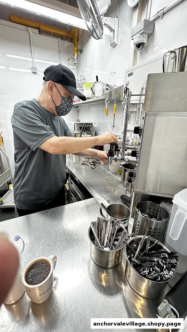 A barista preparing coffee behind the counter at Kopi Kiosk.