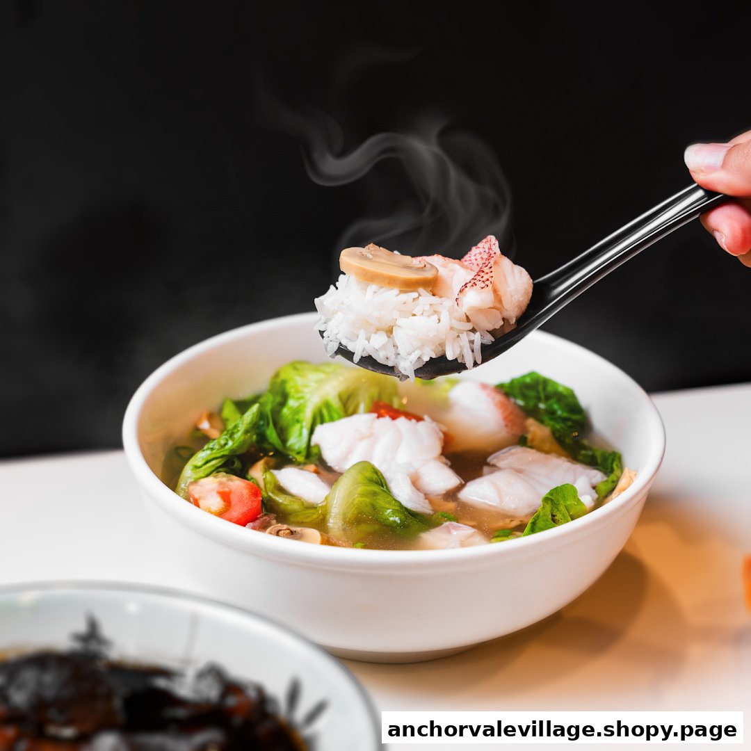 A steaming bowl of fish and vegetable soup with rice and seafood on a spoon, ready to be enjoyed.
