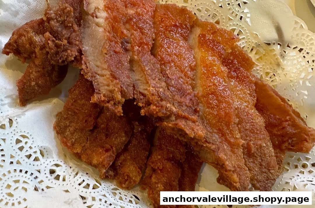 Close-up of crispy fried pork belly slices served on a decorative white doily.