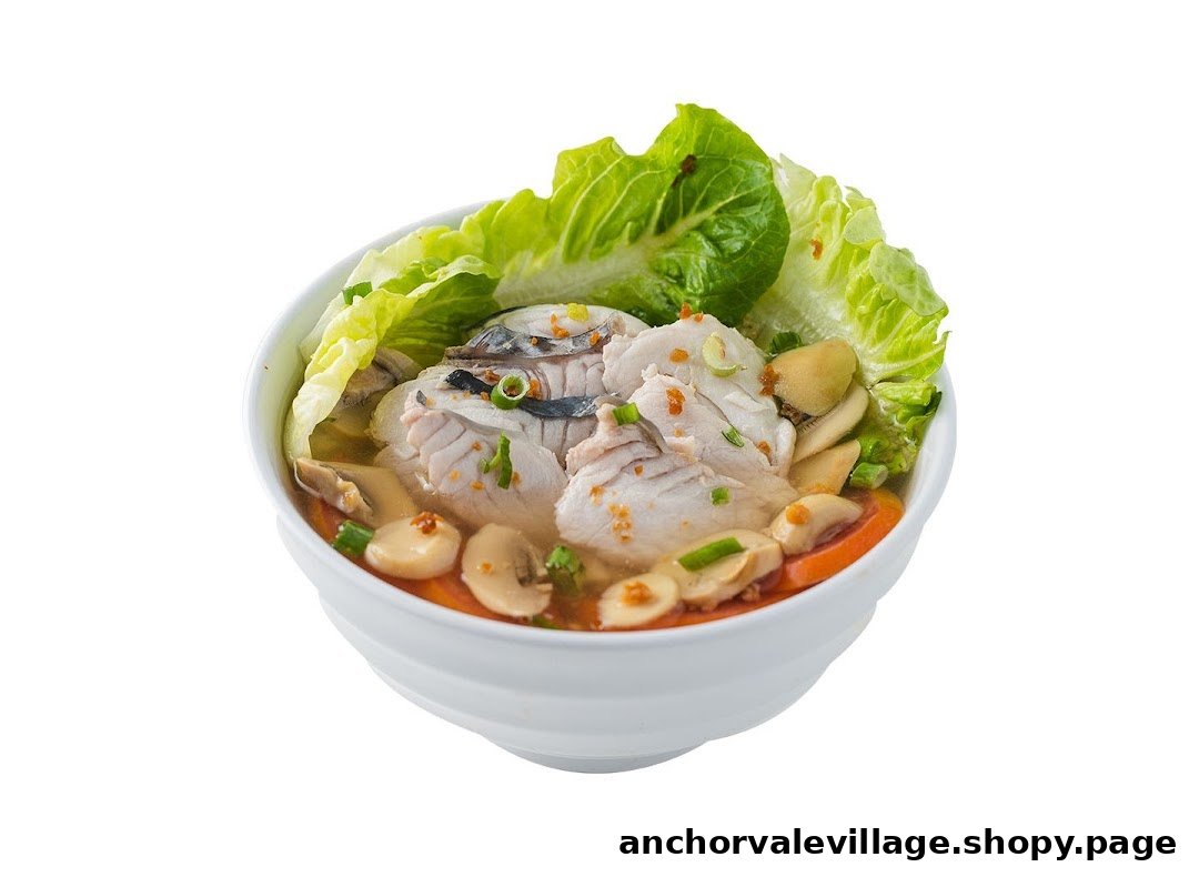 A white bowl filled with fish soup, fresh lettuce, mushrooms, and tomatoes.