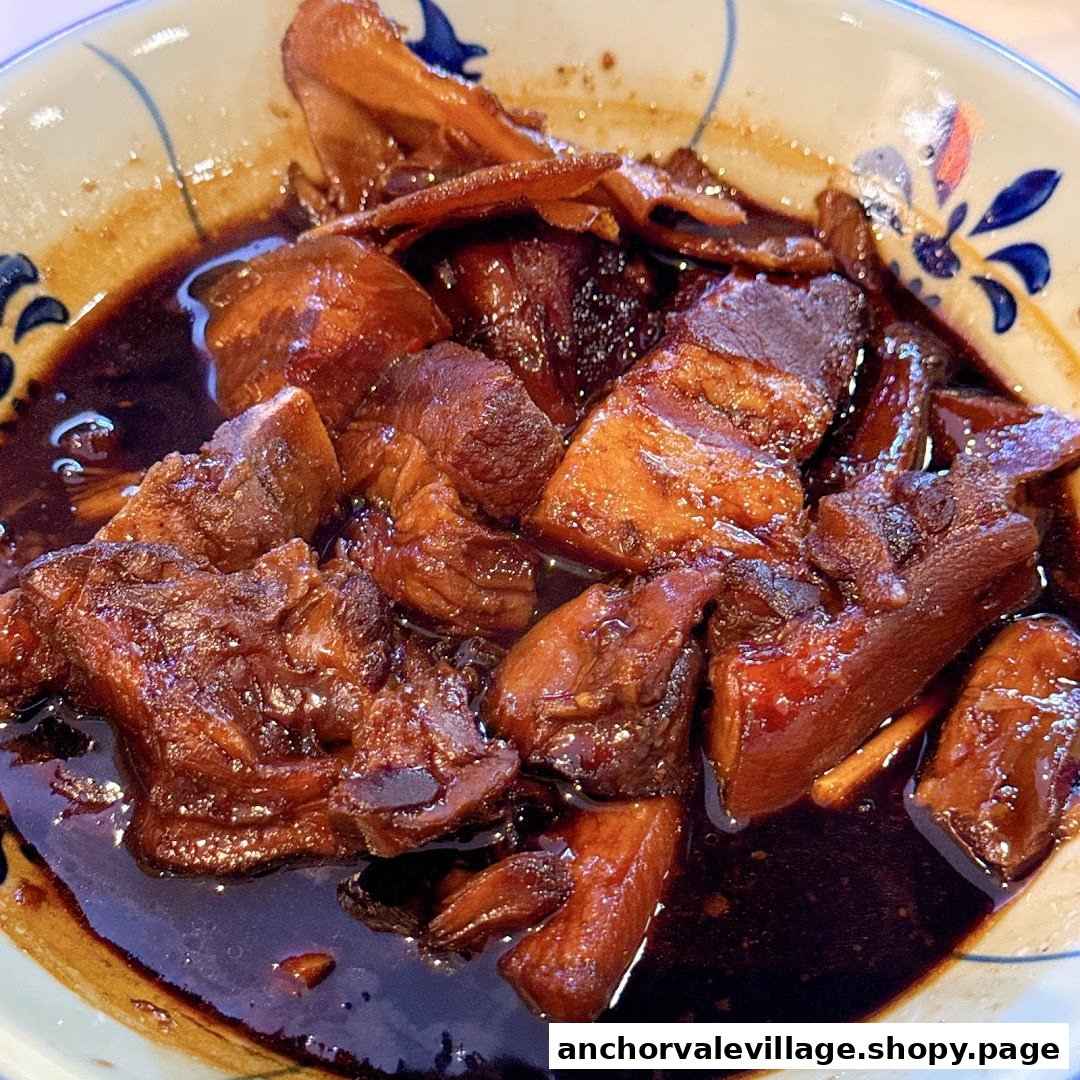 A close-up of rich, dark braised meat and mushrooms in a bowl with a decorative rim.