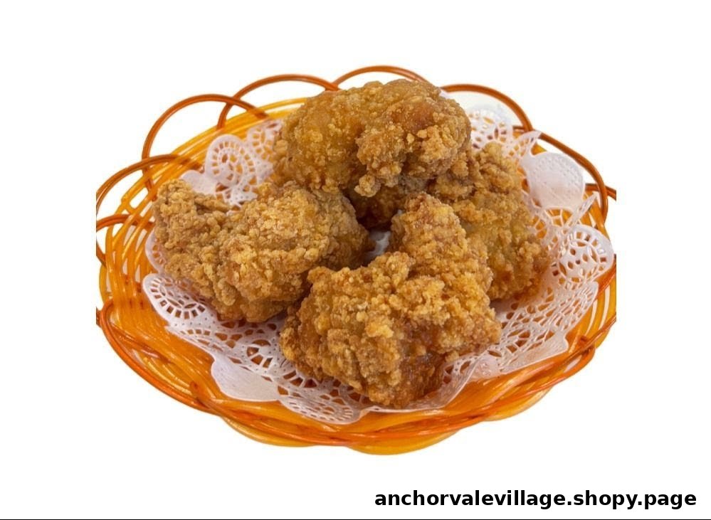 A basket of golden-brown, crispy fried chicken pieces on a white doily.