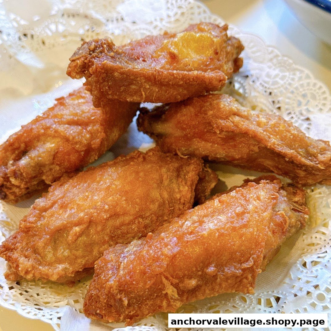 A close-up shot of several golden-brown fried chicken wings served on a white doily.