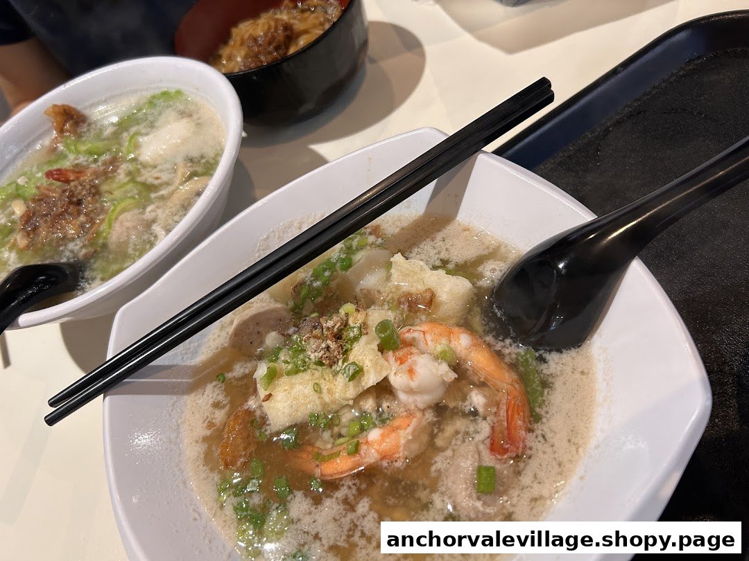 Two bowls of delicious, steaming soup noodles, one featuring fresh prawns, served on a table.
