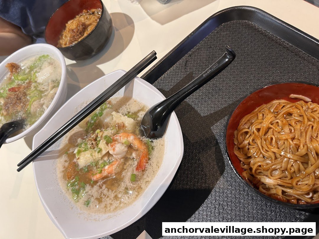 Close-up of several bowls of delicious noodles and soup dishes, including prawn noodles, on a table.