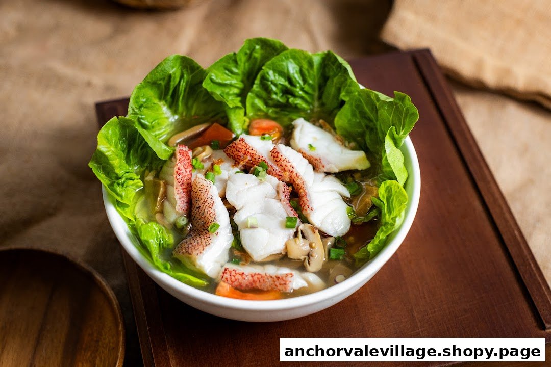 A vibrant bowl of fish soup with fresh vegetables and tender fish fillets, garnished with lettuce.