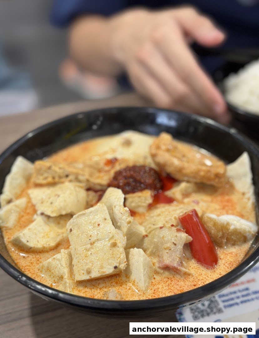 A close-up of a vibrant bowl of Yong Tau Foo in a rich, creamy, and spicy broth.
