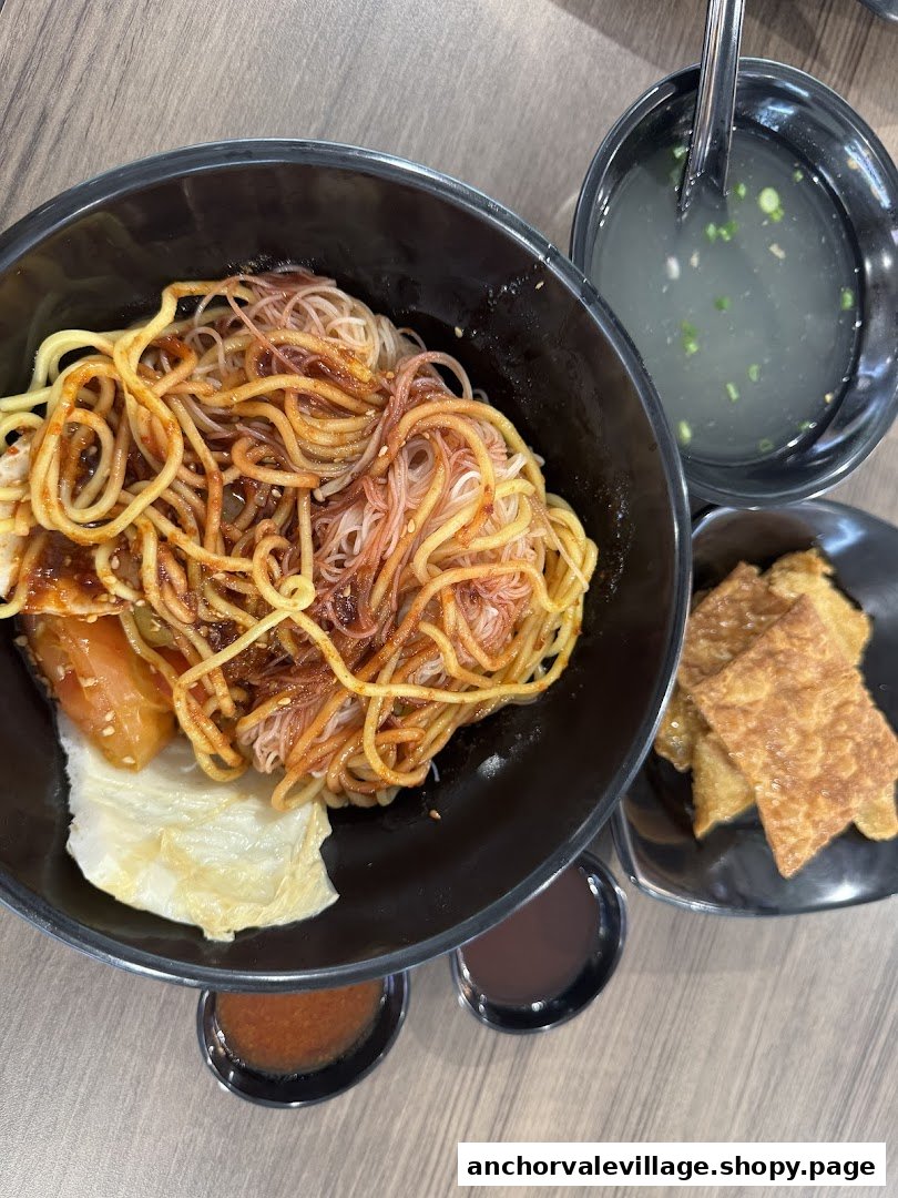 A delicious bowl of Yong Tau Foo noodles with soup and crispy fried wontons on a table.