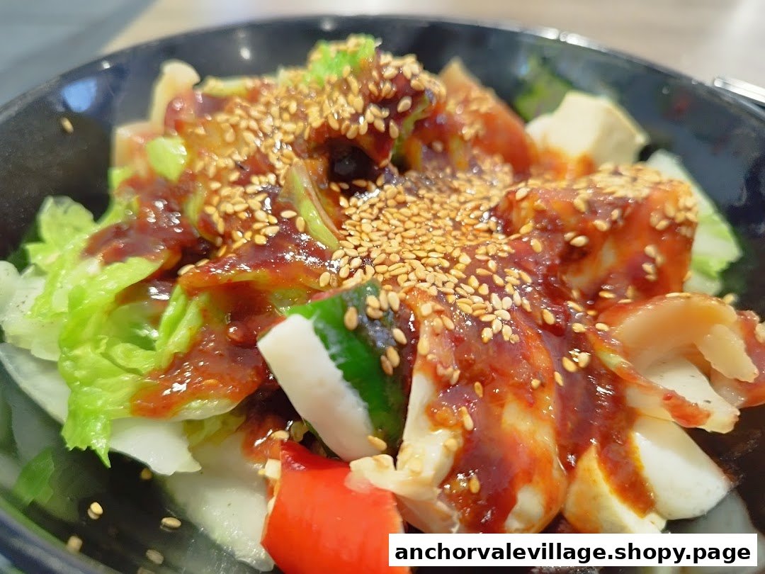 A vibrant bowl of Yong Tau Foo with fresh vegetables, savory sauce, and sesame seeds.