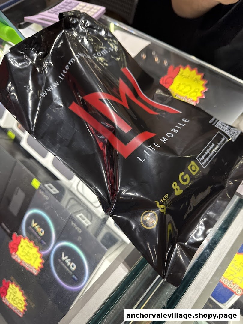 A black Lite Mobile shopping bag on a counter with mobile phone displays and price tags.