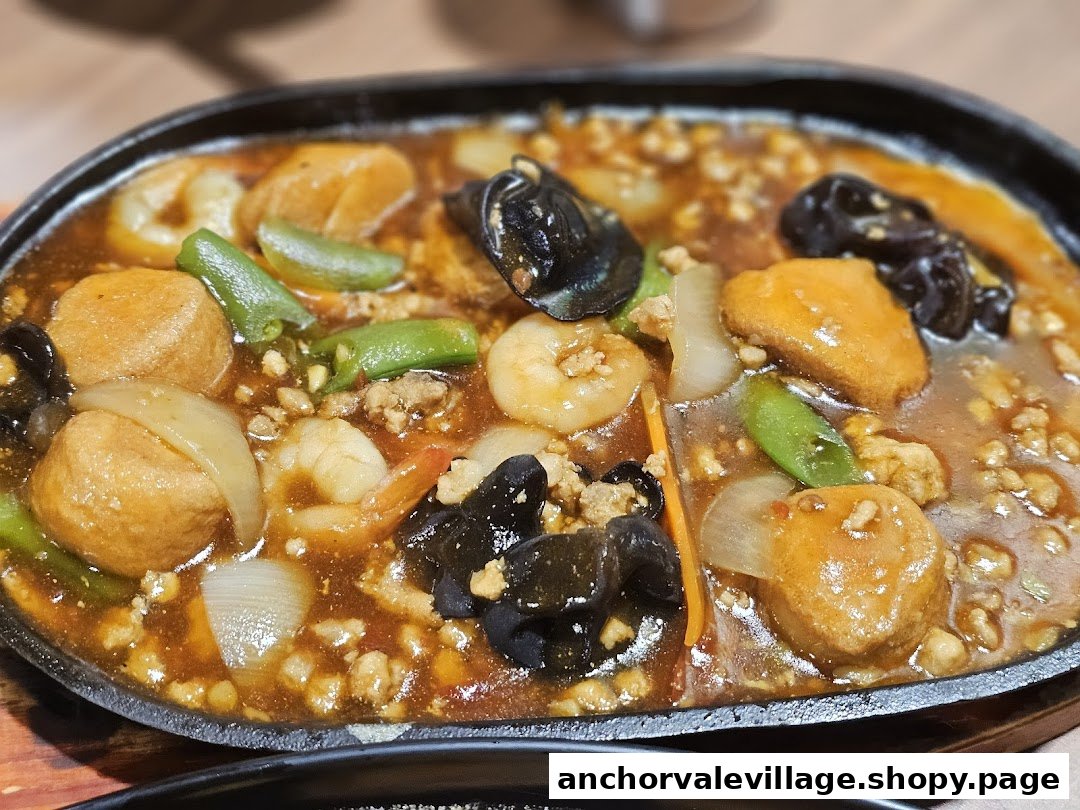 A sizzling plate of seafood, tofu, and vegetables in a rich, savory sauce.
