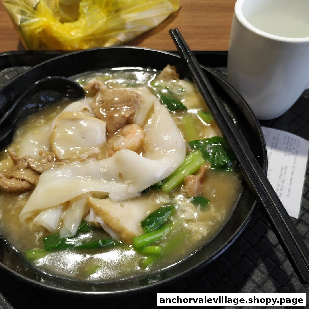 A close-up of a delicious bowl of seafood noodles with vegetables and gravy.