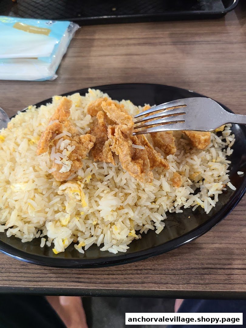 A plate of delicious fried rice with crispy toppings and a fork on a wooden table.
