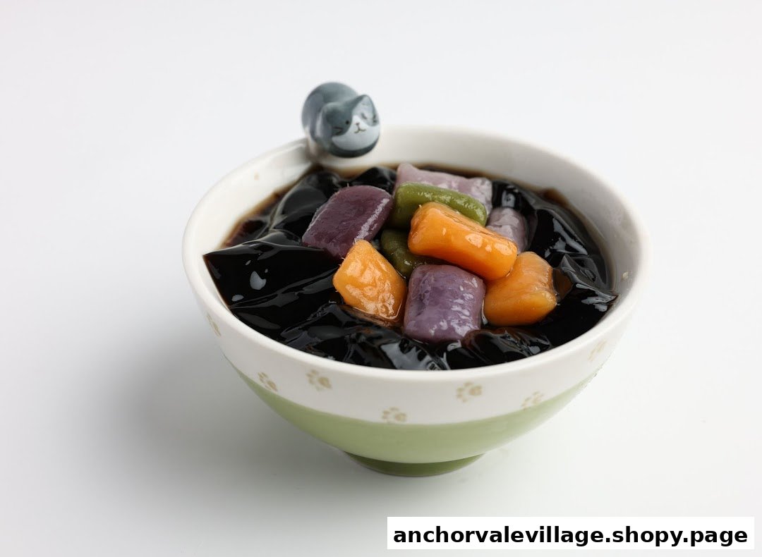 A delightful bowl of grass jelly dessert topped with colorful taro balls and a cute cat figurine.
