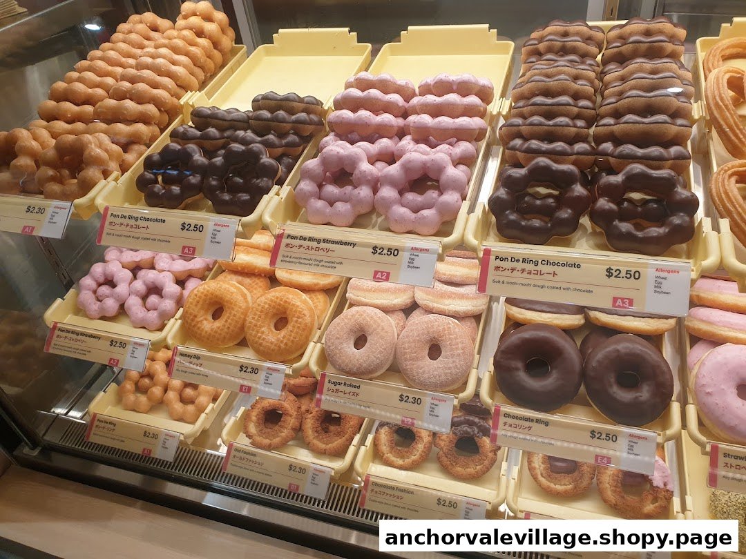 A vibrant display case showcasing a variety of freshly made donuts, including signature Pon De Ring and classic styles.