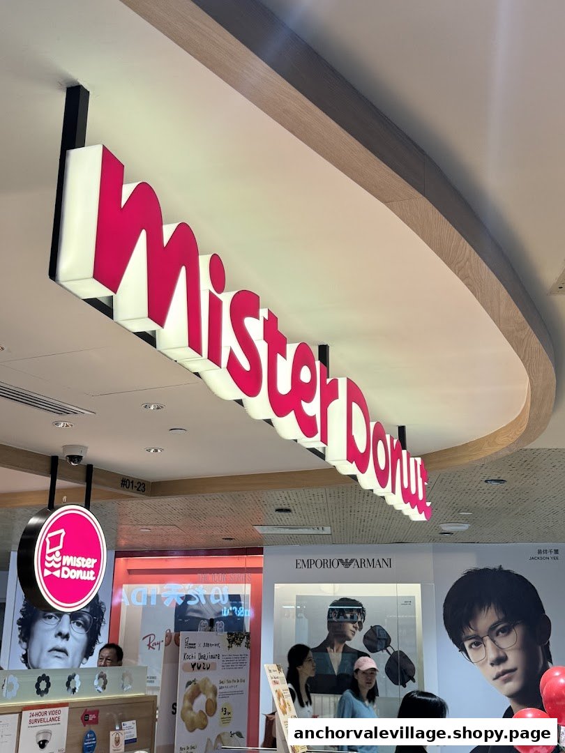 The vibrant Mister Donut sign illuminates the entrance of the Anchorvale Village shop.