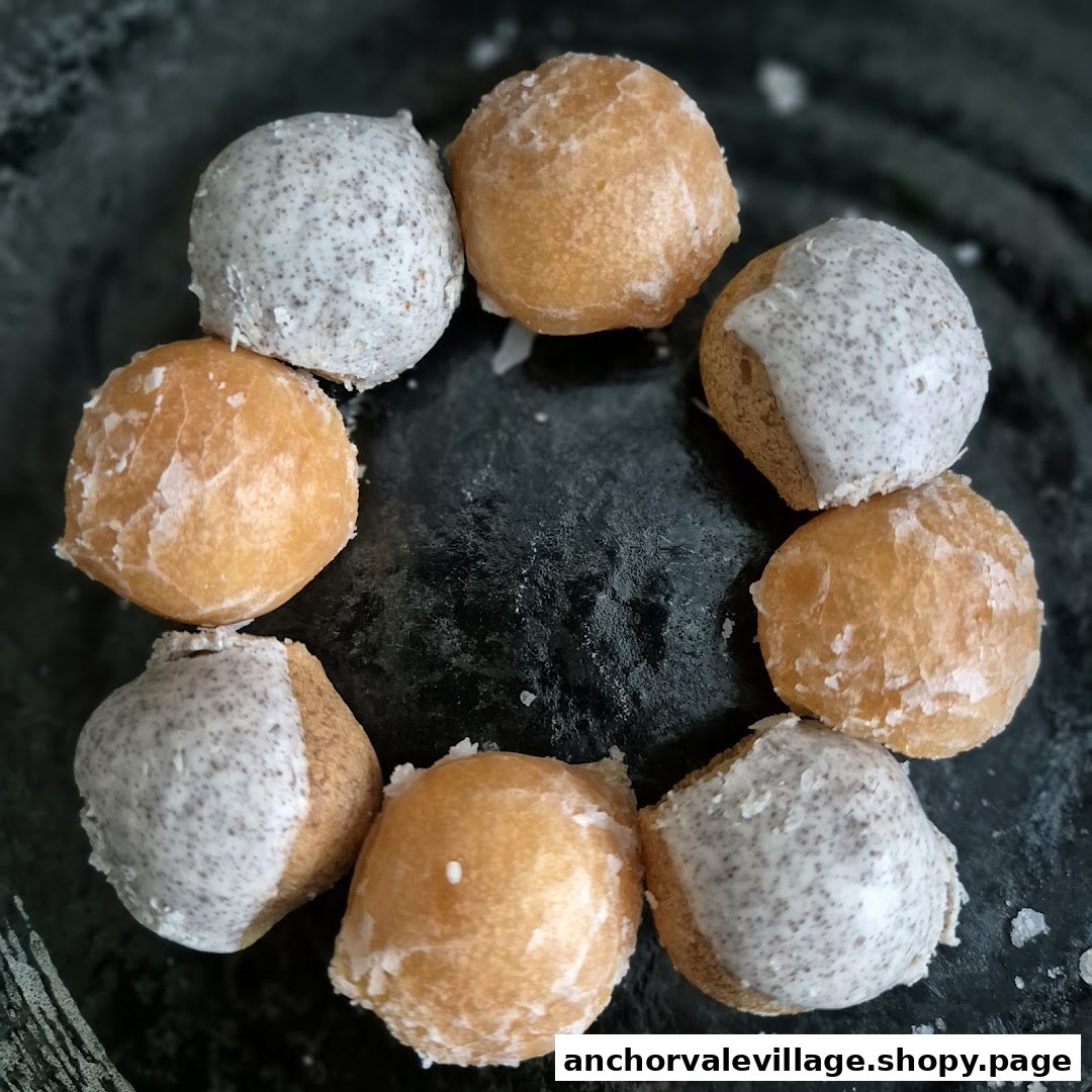 A close-up of assorted donut holes, some glazed and some with cookies and cream frosting, arranged on a dark surface.