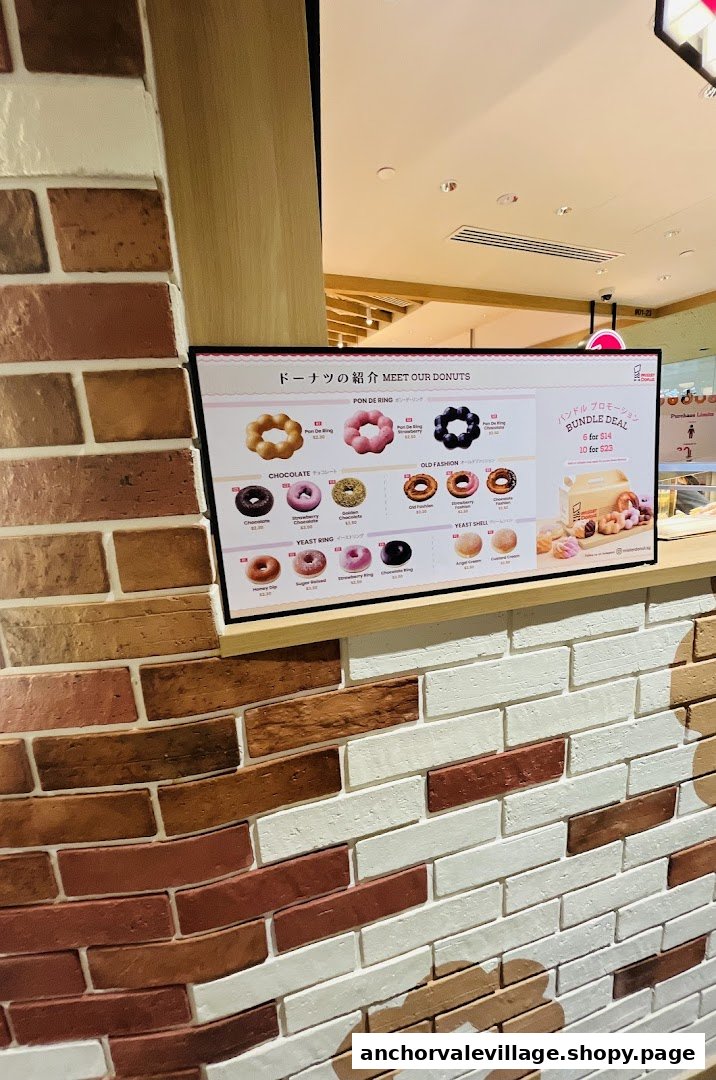 A digital menu board at Mister Donut displaying various donut types, prices, and bundle deals.