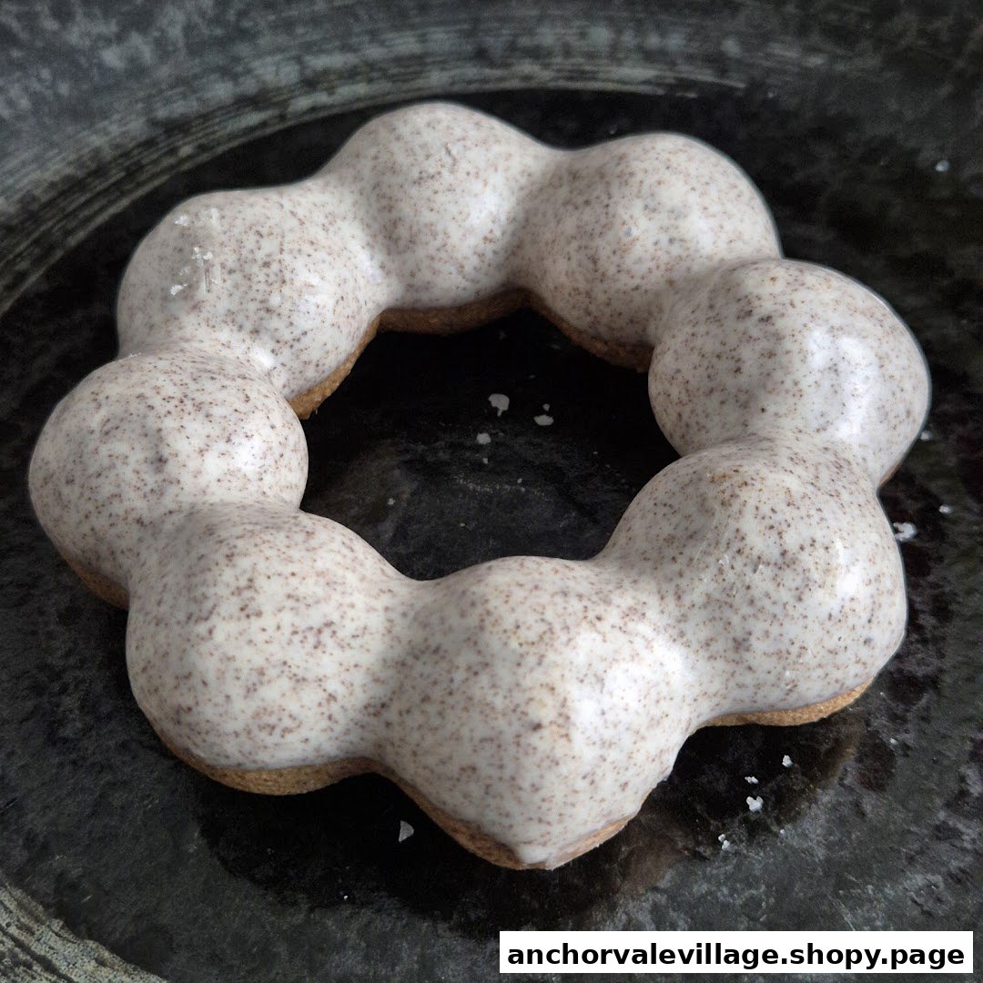 A close-up of a unique mochi donut with a speckled white glaze on a dark plate.
