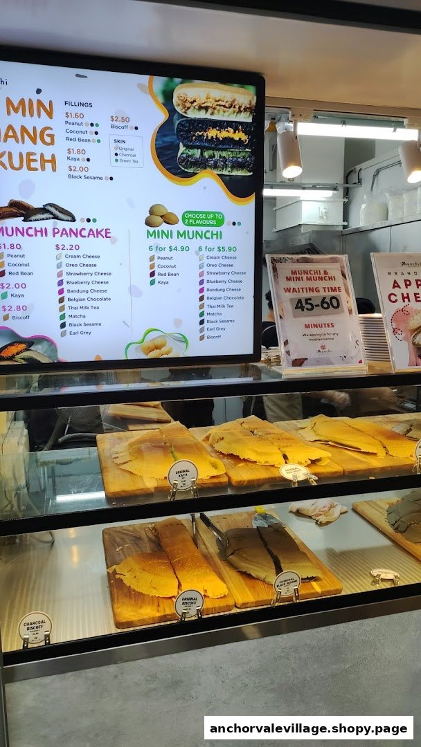 A digital menu board displaying various pancake fillings and mini munchi options, with pancake skins in a display case.