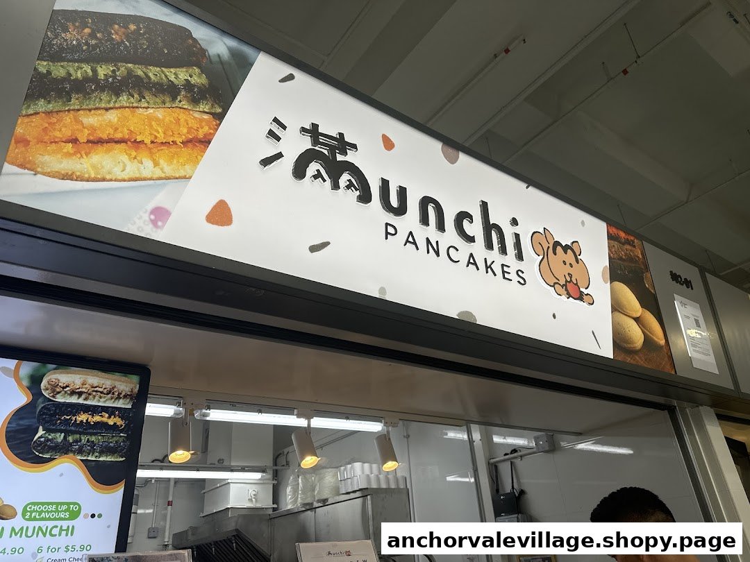 The vibrant sign for Munchi Pancakes, featuring a partial menu board and the shop's counter area.